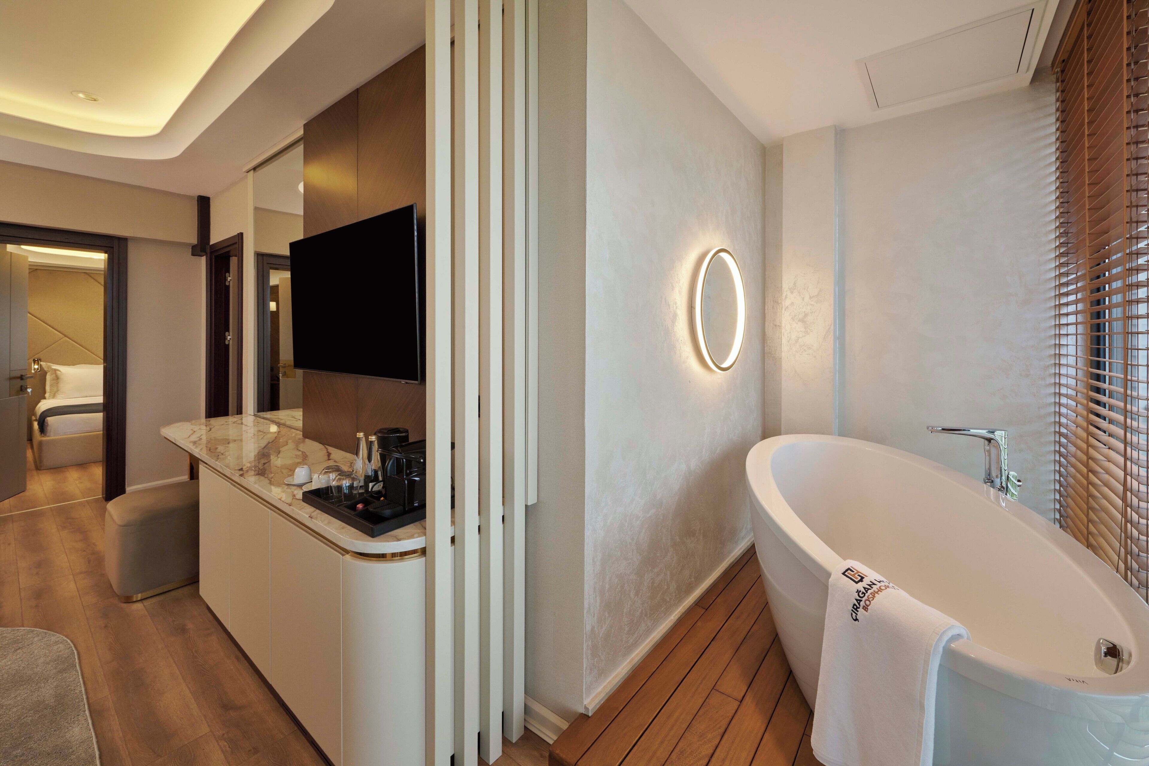 Un bagno moderno con una vasca freestanding, un mobile lavabo con specchio e un televisore a schermo piatto montato a parete.