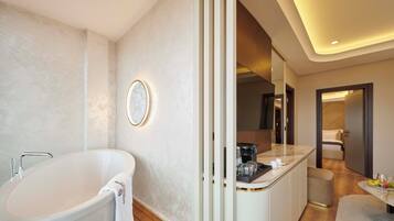 Een moderne badkamer met een vrijstaand bad, een wastafel met spiegel en een aanrecht met toiletartikelen.