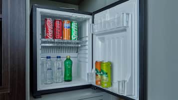 Un refrigerador con estantes llenos de bebidas, incluyendo latas y botellas de refresco.
