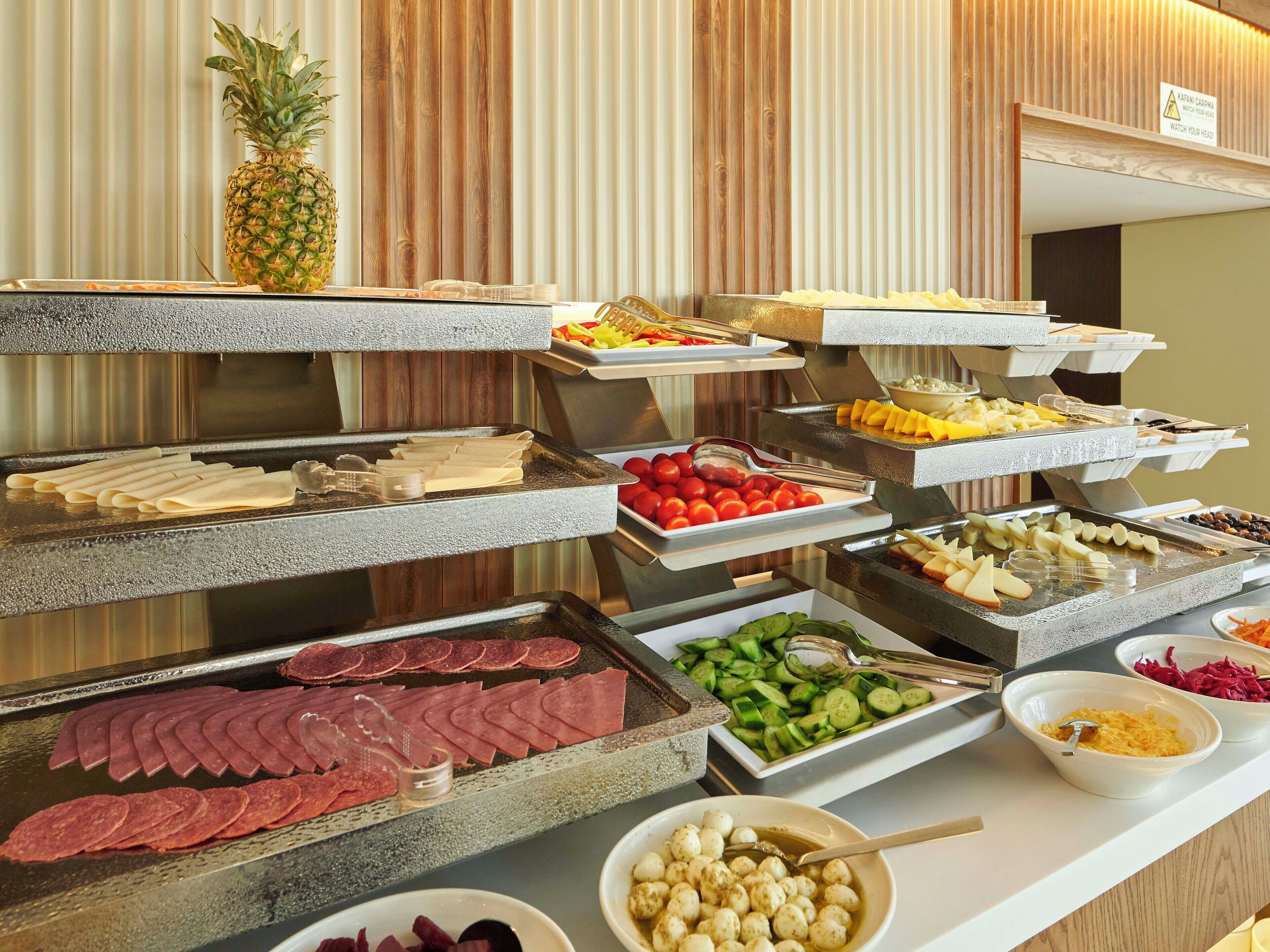 Un buffet proposant une variété de plats, notamment des viandes, des fromages, des fruits et des légumes.