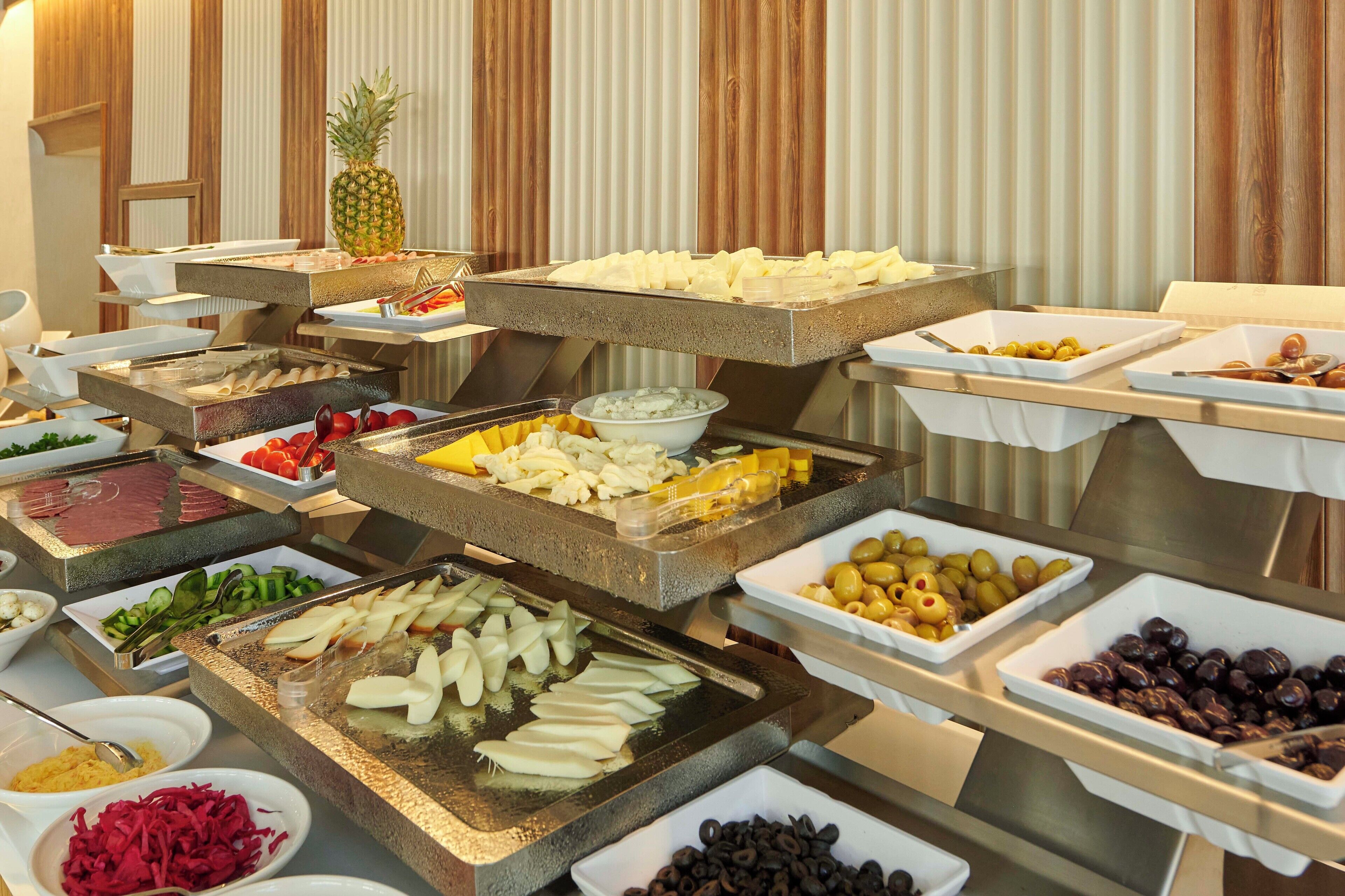 A buffet with various food items including fruits, cheeses, and olives.