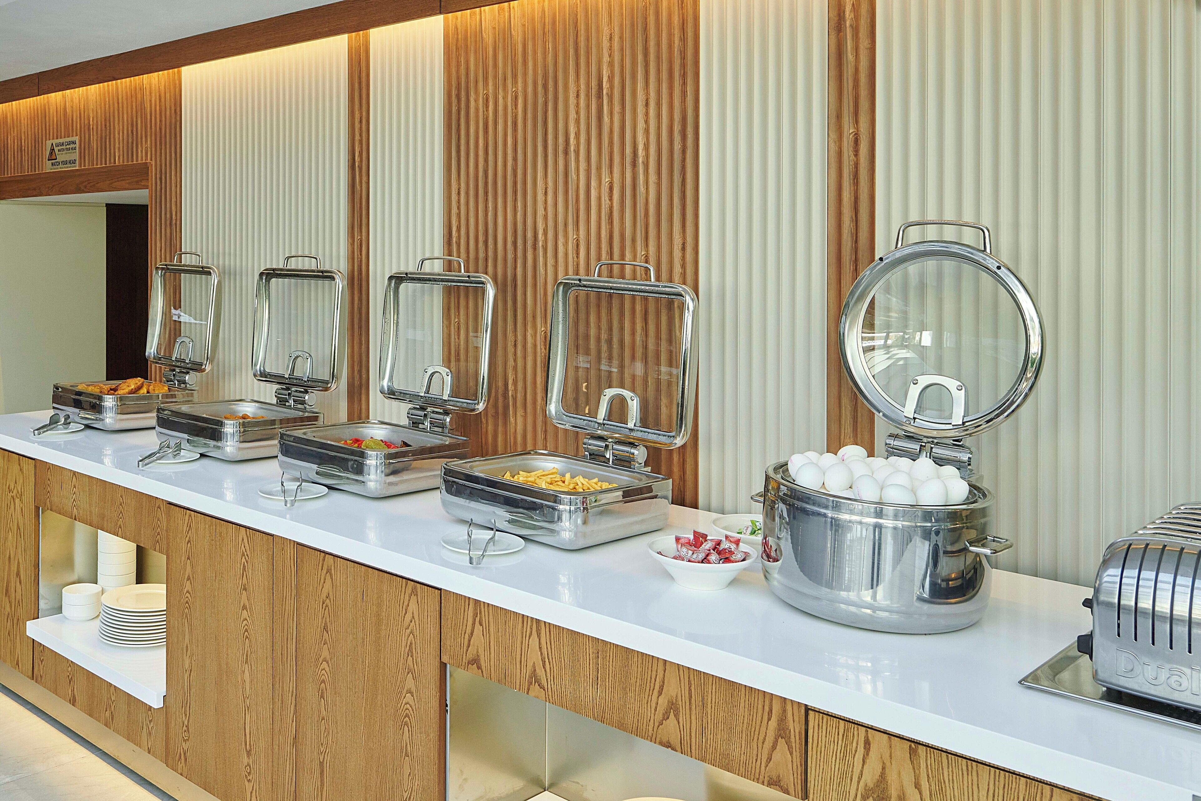 A buffet setup with various food containers and a toaster.