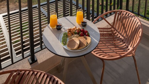 A balcony with a table set for breakfast, overlooking a coastal landscape.