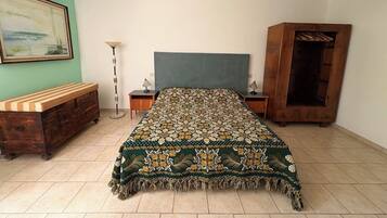 Una camera da letto con un letto, una testiera in legno, comodini, una lampada da terra e un armadio.