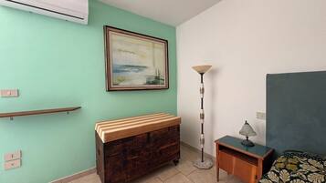 A room with a bed, a dresser, a lamp, and a painting on the wall.