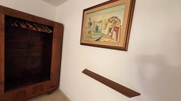 Une pièce avec une armoire en bois, un tableau abstrait encadré et une étagère murale.