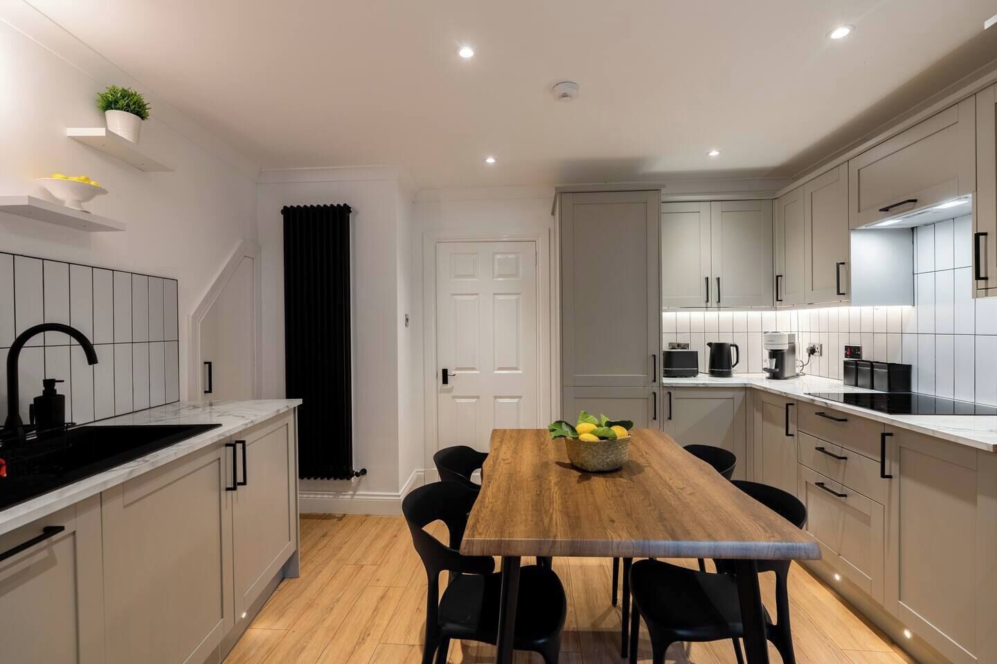 A modern kitchen with a wooden dining table, black chairs, and a black faucet.