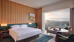A hotel room with a bed, bedside tables, a chair, a small table with a tray, and a large window with a city view. - Hyatt Regency Kuala Lumpur At Kl Midtown (Kuala Lumpur)
