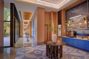 Een moderne hotel lobby met een receptiebalie, een koffiebar en een vloer met een patroon.