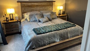 A bedroom with a wooden headboard, two bedside tables with lamps, a bed with a patterned bedspread and pillows, a framed picture above the headboard, and a carpeted floor. - Charming 3-bedroom, 2-12/ bath house with AC, WiFi in peaceful Fortville (Fortville)
