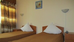 Ein Hotelzimmer mit zwei Einzelbetten, einem Nachttisch mit Lampe und einem kleinen Tisch mit Telefon.