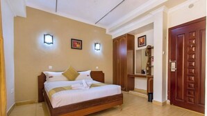 A bedroom with a wooden bed, beige walls, and a wooden wardrobe. - Miale Hotel  (Nakuru)