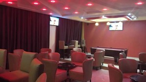 A room with red ambient lighting, a pool table, and multiple seating areas. - Miale Hotel  (Nakuru)