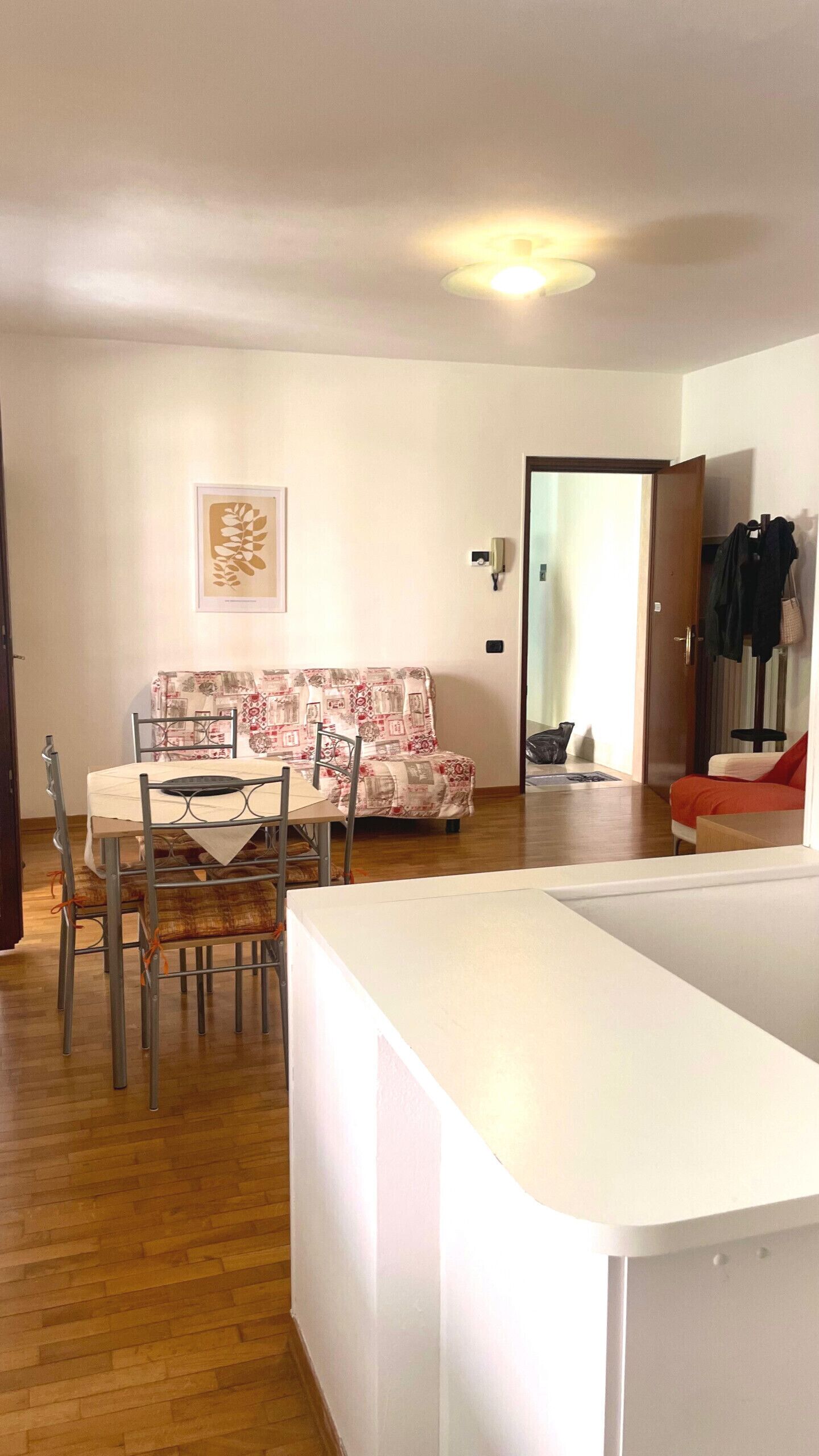 A living room with a dining area, a sofa, and a coat rack.