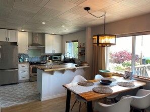 Una cocina moderna con una isla central, electrodomésticos de acero inoxidable y un comedor con mesa y sillas de madera.