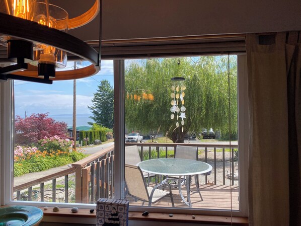 Habitación con vista a un jardín, una mesa con sillas y una lámpara colgante.