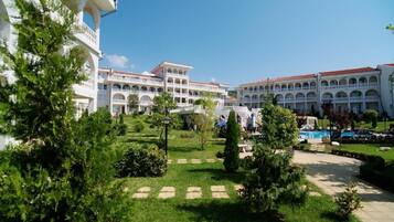 A hotel with multiple white buildings, a swimming pool, and a well-maintained garden.