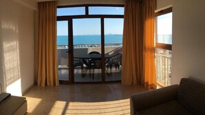 Una habitación con un amplio ventanal corredera que da a un balcón con vista al mar.