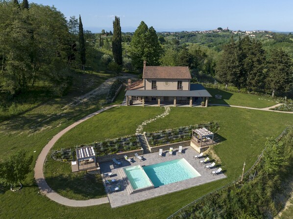 Una casa grande con piscina, mobiliario exterior y jardín.