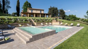 A pool area with multiple lounge chairs and a stone staircase leading to a house. - Agriresort Bacaringhe 13, Emma Villas (Terricciola)