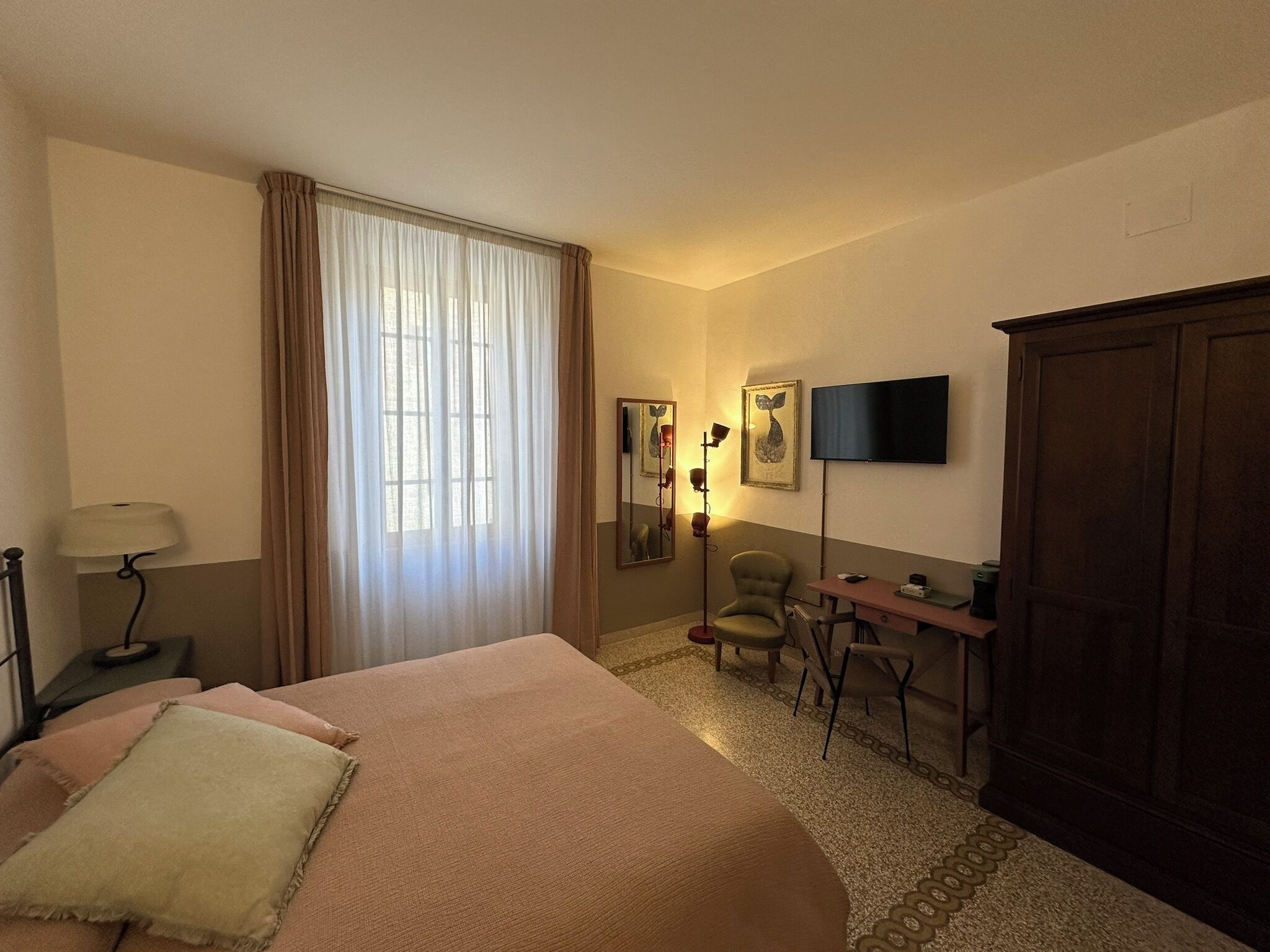 Una habitación de hotel con cama, escritorio, silla, televisión y armario.