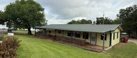 A single-story building with a porch, a covered area, and a small adjacent structure.