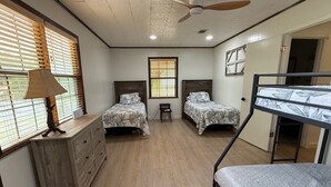 Un dormitorio con dos camas, un aparador, un escritorio y una litera.