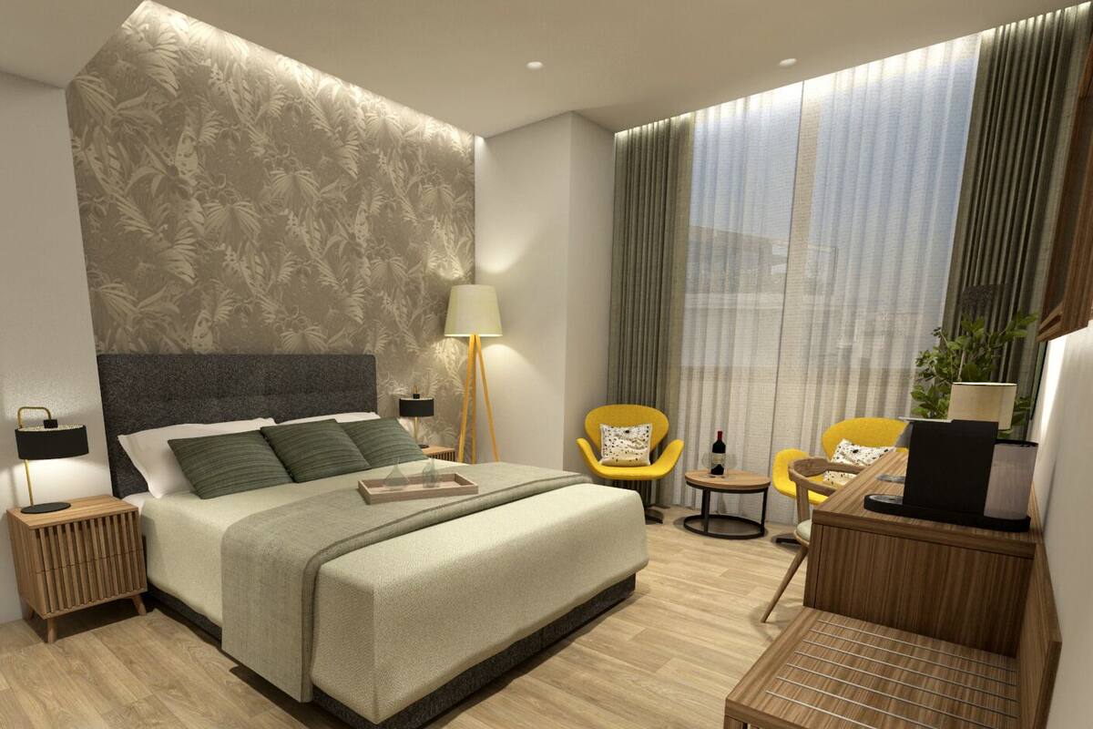 Habitación de hotel moderna con una cama grande, un escritorio, dos sillas, una lámpara y vistas a la ciudad a través de amplias ventanas.