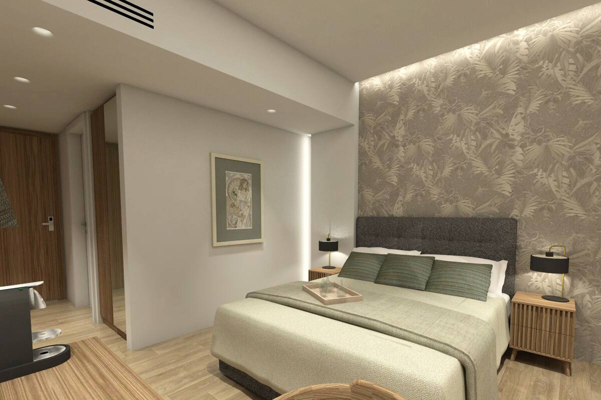 Un dormitorio moderno con una cama grande, dos mesitas de noche, una mesita auxiliar y un cuadro enmarcado en la pared, además de una puerta que da a otra habitación.