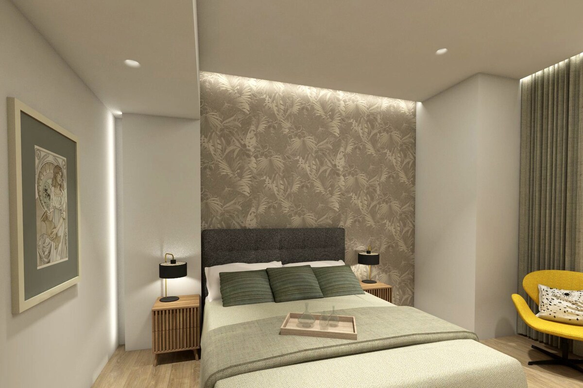 A modern bedroom with a large bed, two bedside tables, a framed picture on the wall, and a yellow chair.