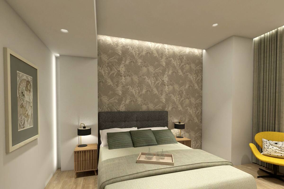 A modern bedroom with a large bed, two bedside tables, a framed picture on the wall, and a yellow chair.