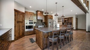 A spacious kitchen with wooden cabinets, a central island with bar stools, and pendant lighting.