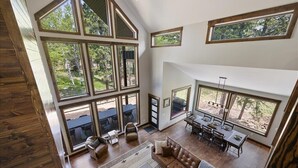 A spacious living area with large windows, a dining table, and a cozy seating arrangement.