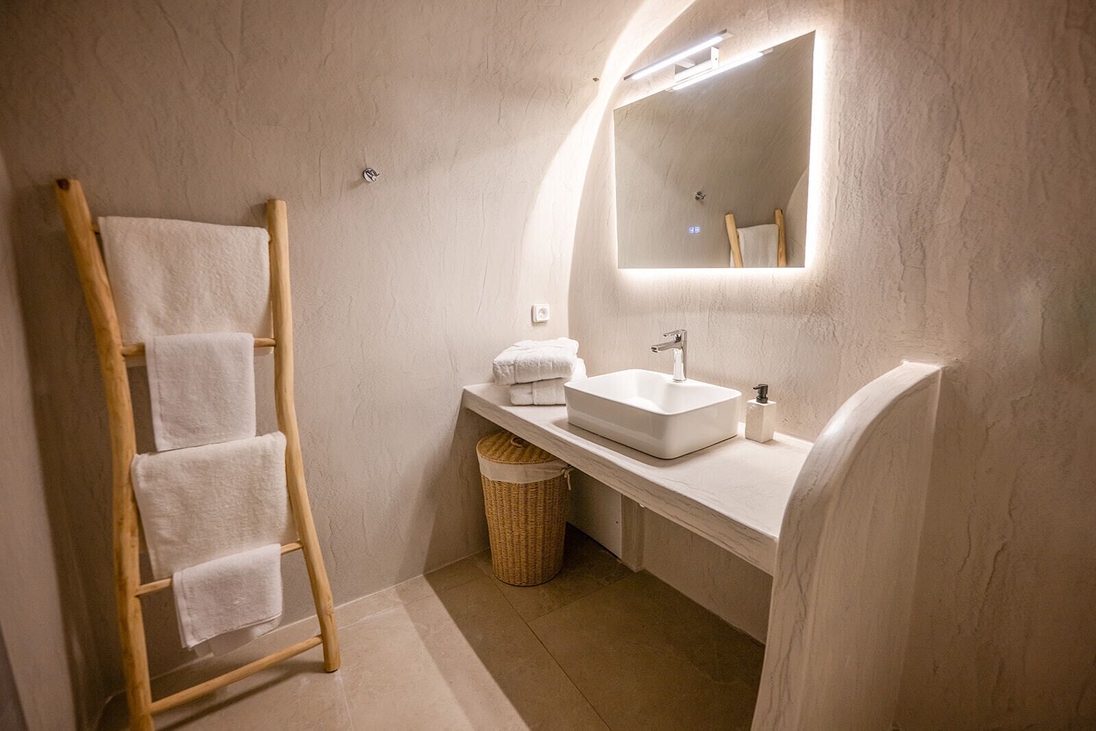 A modern bathroom with a wooden towel rack, a white sink, and a mirror.