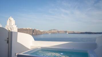 A white infinity pool with a clear view of the sea and distant cliffs.