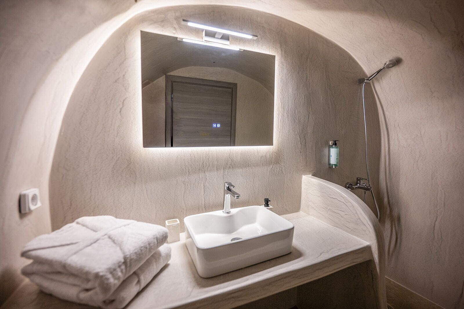 A bathroom with a white sink, a mirror, a towel, and a shower.