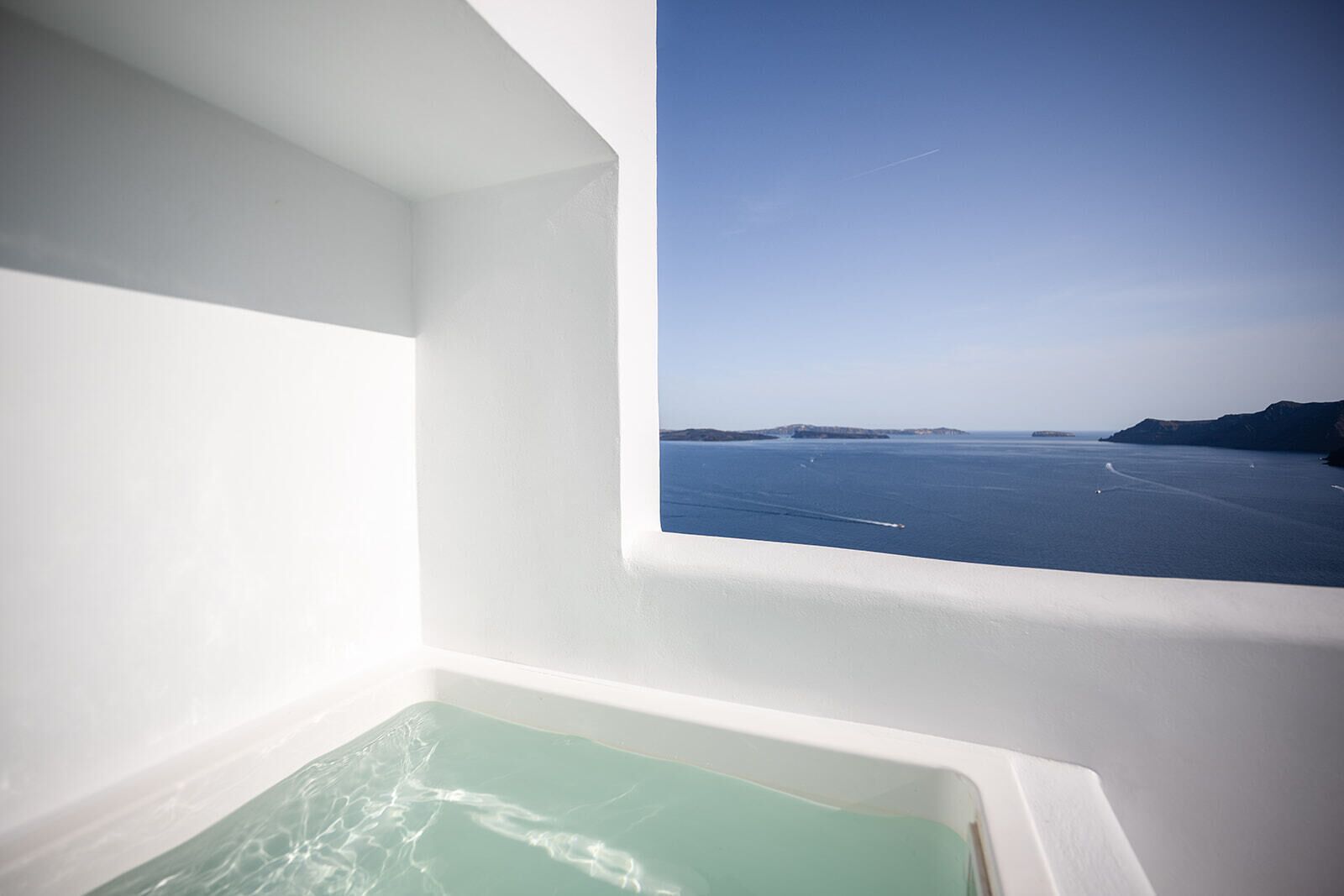 A bathtub with a view of the sea and a distant island.
