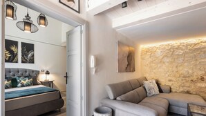 A modern living room with a sofa, a bed, and a stone accent wall. - Maison Beata - Two Bedroom Apartment, Sleeps 5 (Avola)