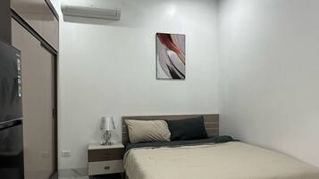 Een moderne slaapkamer met een bed, nachtkastje en een koelkast.