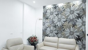 A modern living room with a ceiling fan, a floral wallpaper, a beige sofa, a round coffee table, and a floor lamp. - Homestay-Kim Mã -Giang Văn Minh (Hanoi)