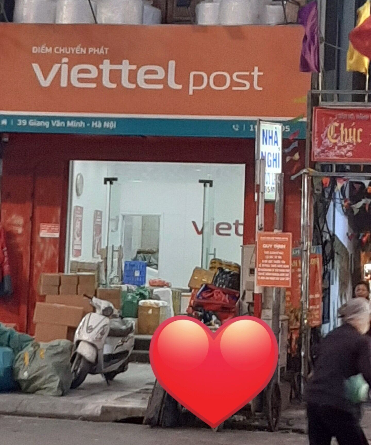 A storefront with the sign 'viettel post' and various items like boxes and a scooter outside.