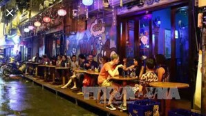 A row of outdoor dining tables along a canal, with people seated and eating. - Homestay-Kim Mã -Giang Văn Minh (Hanoi)