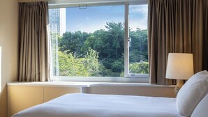 A hotel room with a large bed, a window with curtains, and a lamp on the nightstand. - Deluxe Triple Room hotel with AC, fitness room, WiFi in amazing Minato City (Minato City)