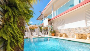 A swimming pool with a waterfall feature, lounge chairs, and a stone wall. - Vacation Home for 20 Guests with 2 Private Pools (Aguada)