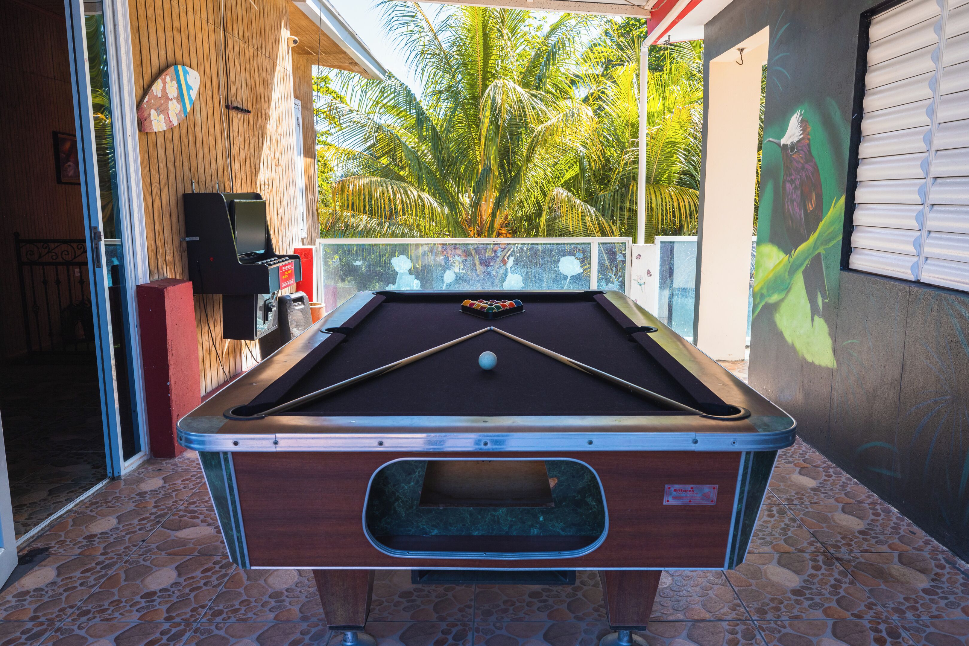 A pool table with a billiard cue, a speaker, and a glass rail.