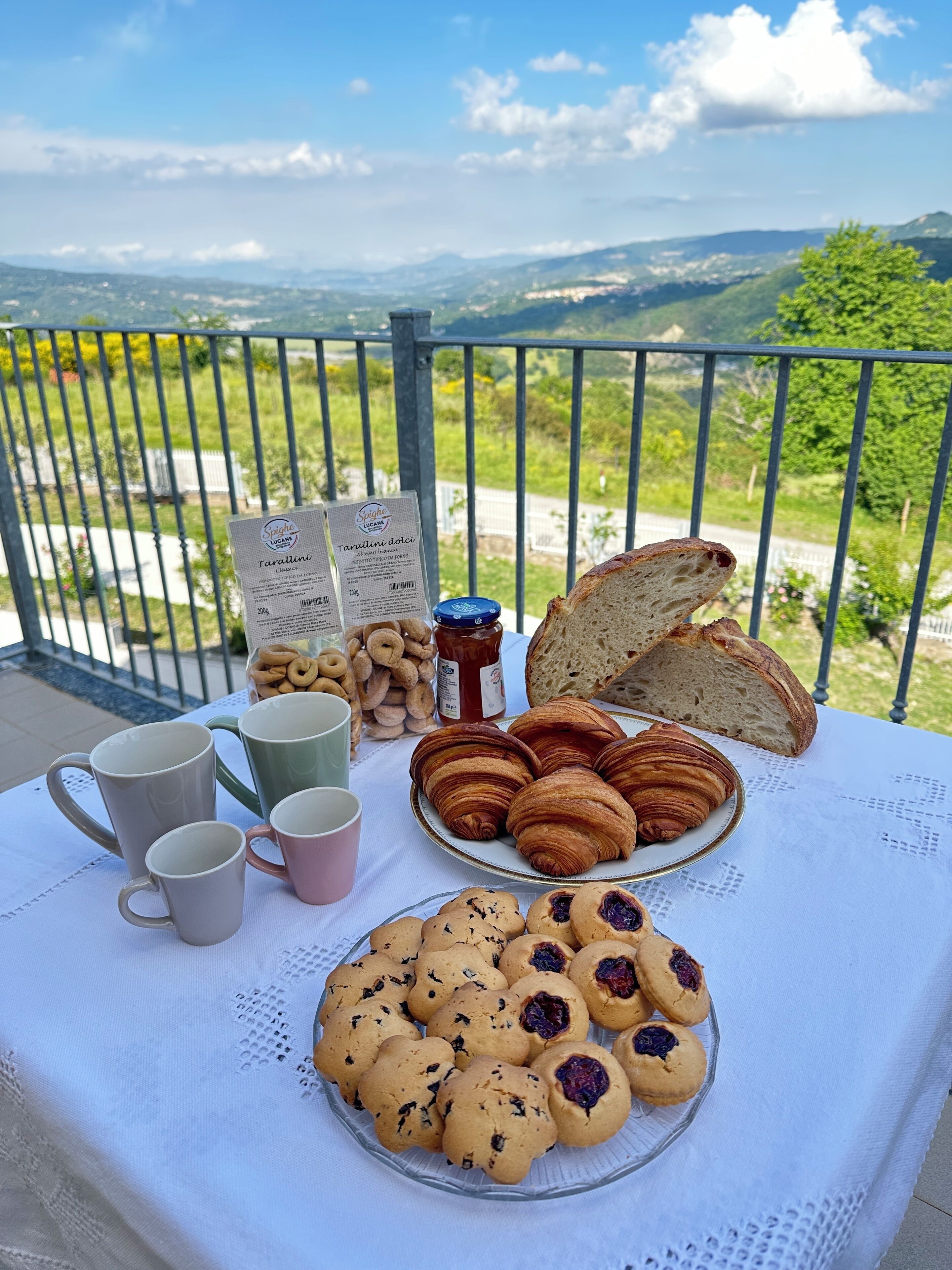 Ein Tisch mit Gebäck, Brot und Kaffeetassen auf einem Balkon mit schöner Aussicht.
