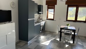 Une cuisine moderne avec des meubles gris, un four encastré et un coin repas comprenant une table et des chaises.
