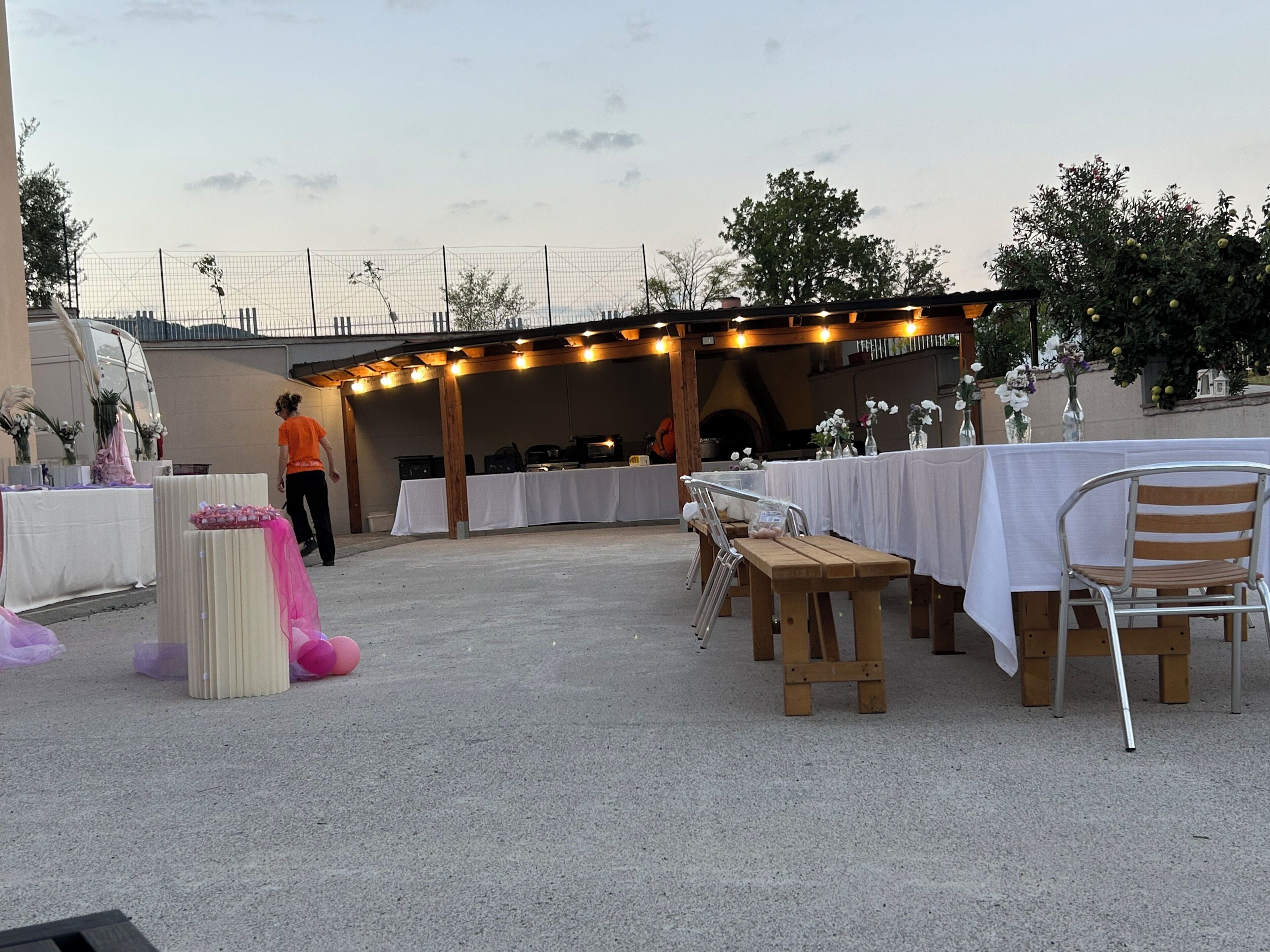An outdoor event space with tables set up for dining, a stage area, and a seating arrangement.