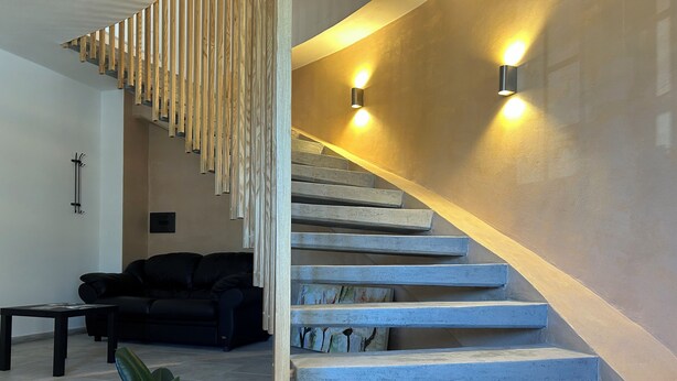Un escalier moderne avec une rampe en bois et des appliques murales.