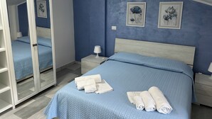 Une chambre à coucher avec un lit, une table de chevet, un miroir et deux tableaux encadrés accrochés au mur.